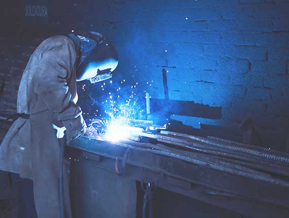 A worker performing welding process. Blue flames reflected while welding